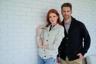 A woman and a man wearing grey and black Redwood sweaters.