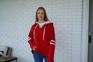 A woman wearing a red hoodie with white stripes on the sleeves.