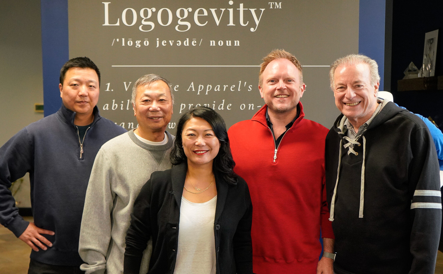 A group of people standing in front of a sign reading "logogevity".