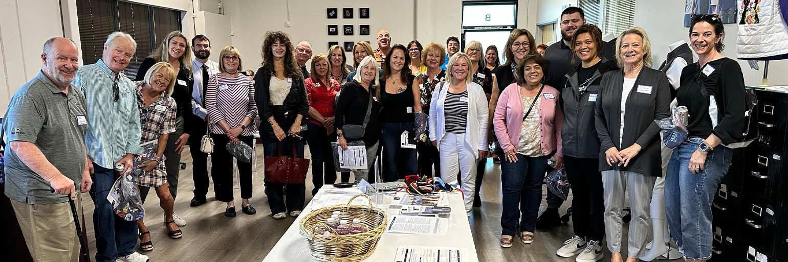 A group of people wearing nametags surrounding a table in the new Vantage facility. The table has various brochures and a basket full of water bottles.