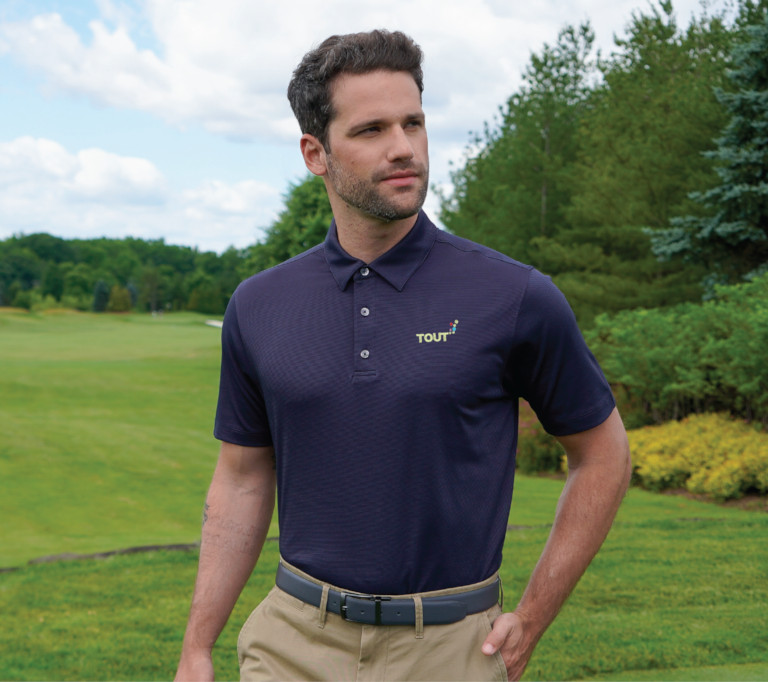 A man wearing a navy polo on a golf course.